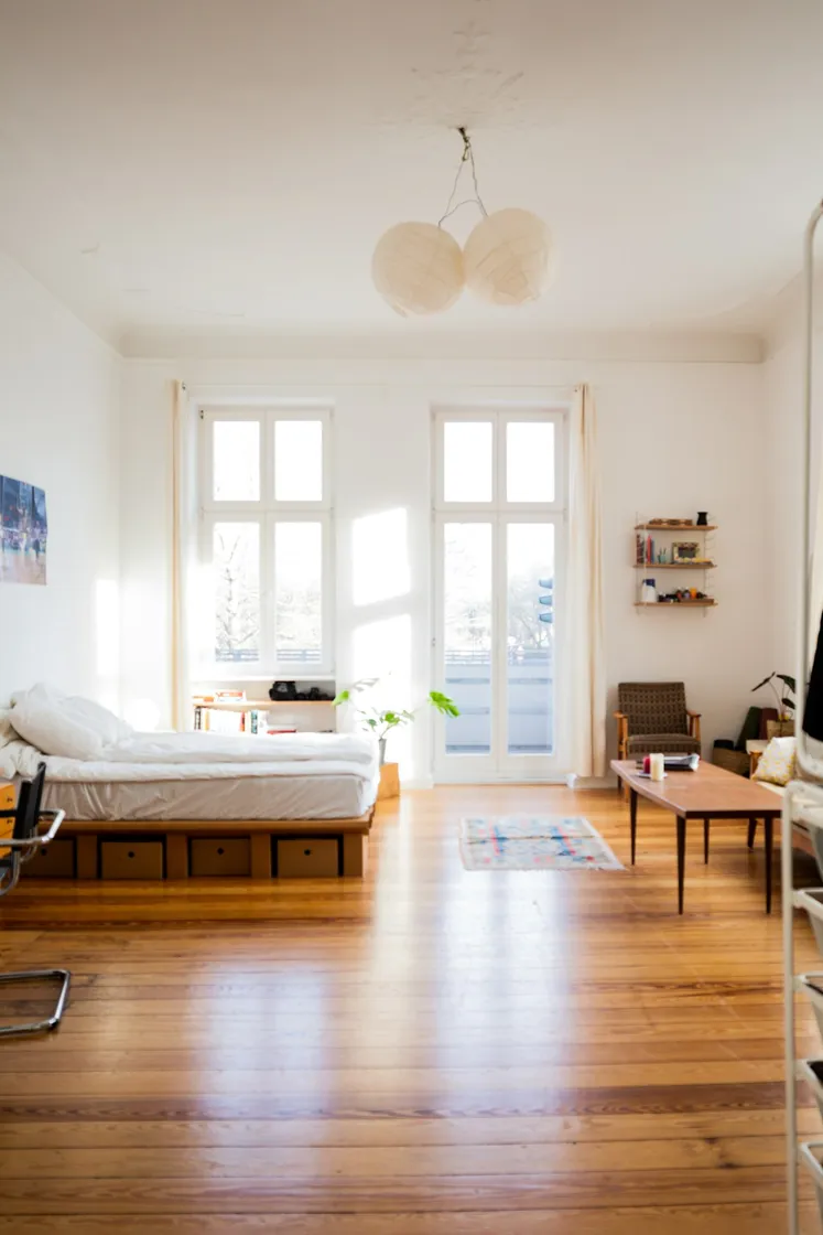 A bright bedroom as photographed: bare mattress, tall windows, wood floor